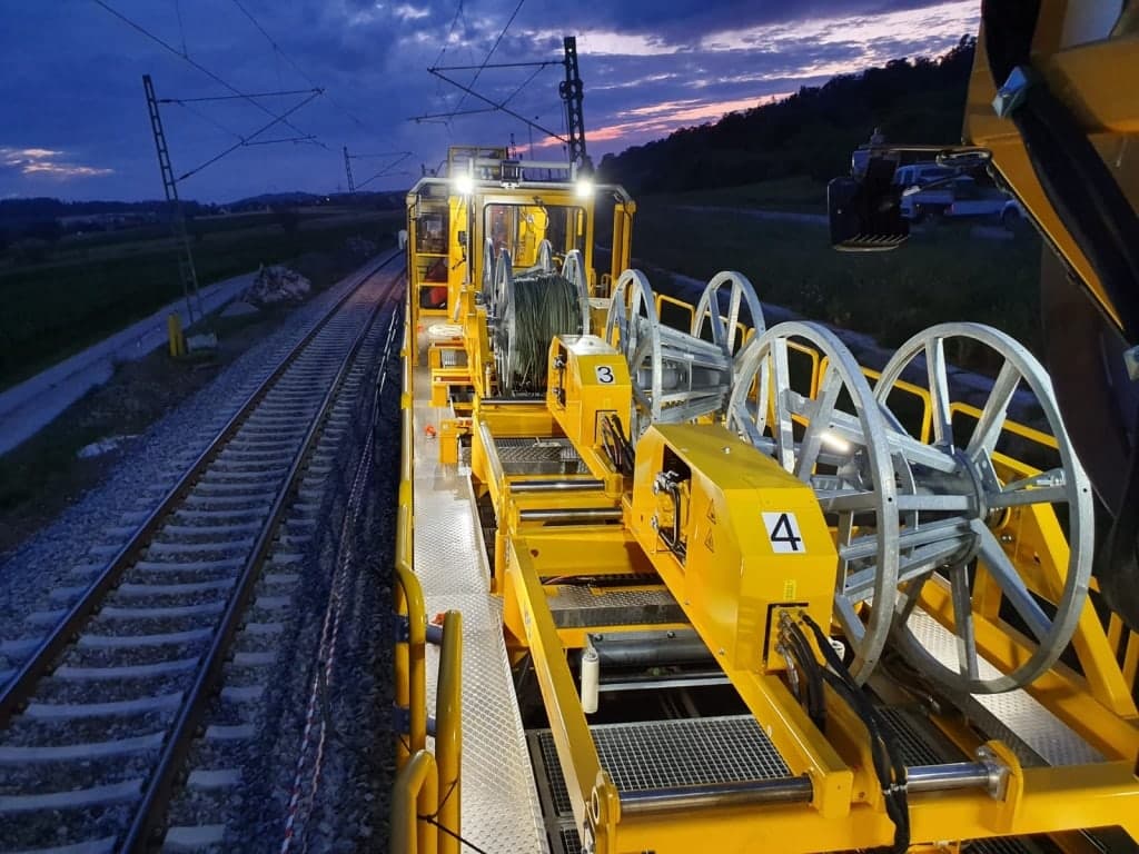 Beleuchtete ZECK-Verlegeeinheit mit Trommelböcken auf einem Bahnwagen bei Nacht