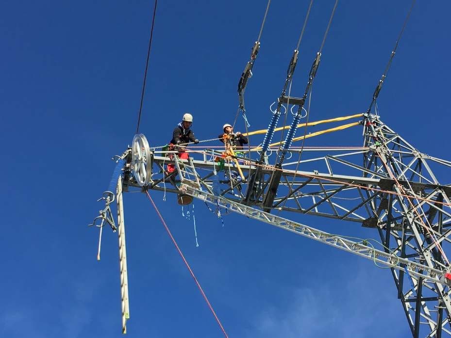Fitters on an overhead line tower with a stringing block